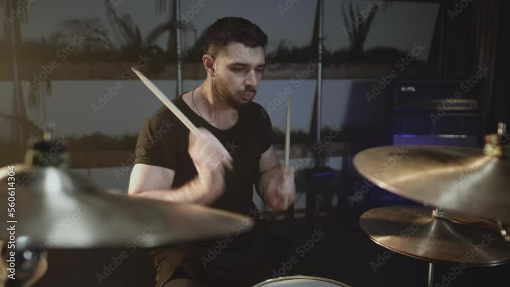 A young attractive male drummer plays with sticks on a drum kit. Makes