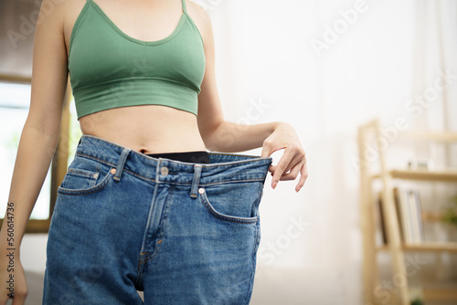 Asian woman dieting Weight loss. Slim woman in oversize jeans 