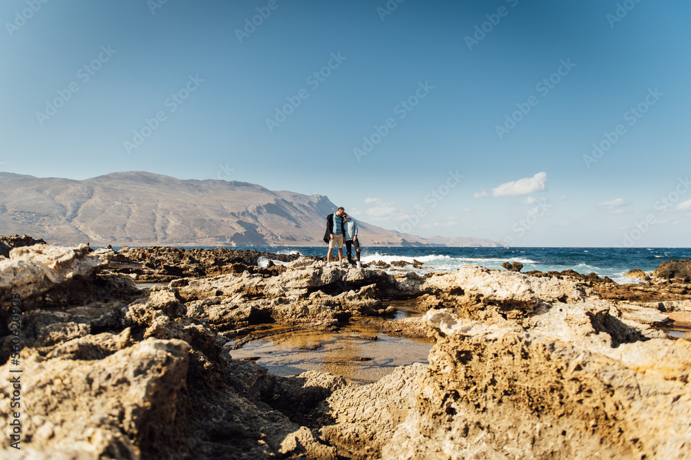 Happy couple walking and hugging on the shores of the mediterranean sea