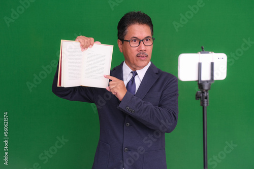 A lecturer running his online class from home using his smartphone in front of him photo