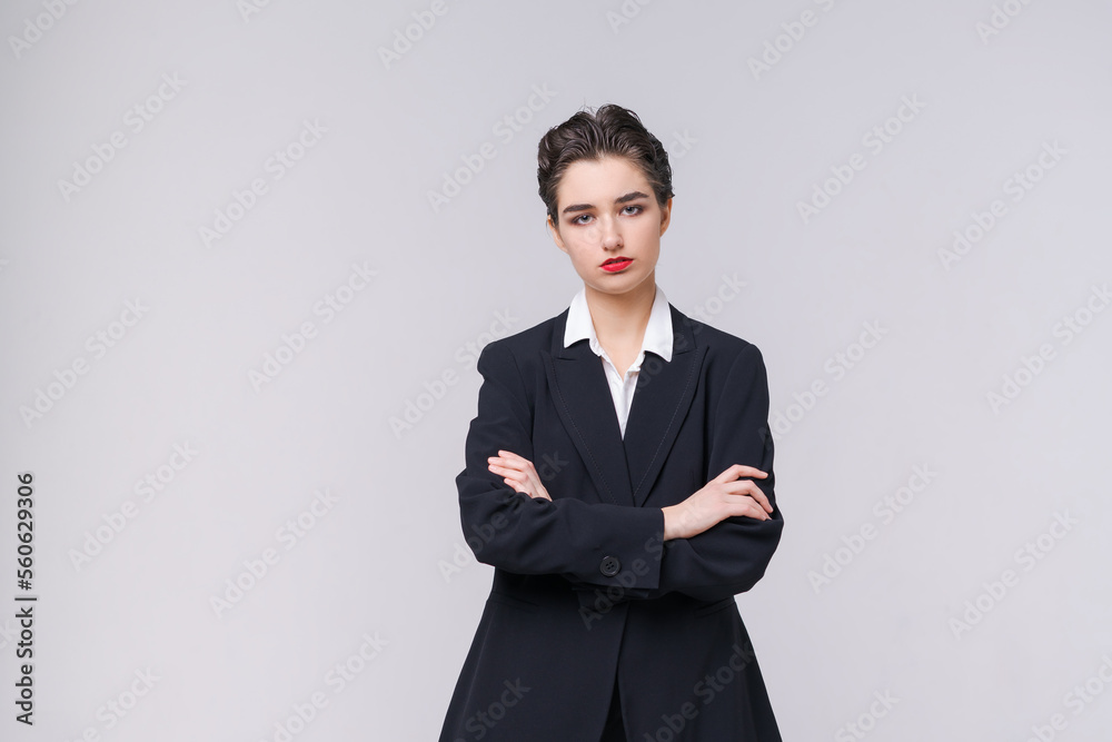 Attractive business young woman posing in business black suit with short haircut and red lips on gray background with copy space. Caucasian girl professional worker Attractive business young woman posing in business black suit with short haircut and red lips on gray background with copy space. Caucasian girl professional worker