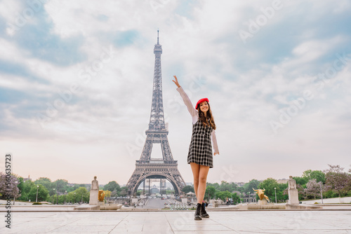 Beautiful young woman visiting paris and the eiffel tower. Parisian girl with red hat and fashionable clothes having fun in the city center and landmarks area © oneinchpunch