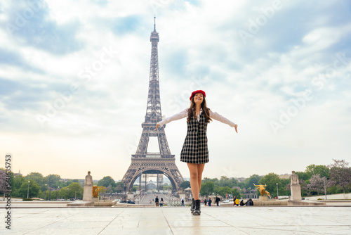 Beautiful young woman visiting paris and the eiffel tower. Parisian girl with red hat and fashionable clothes having fun in the city center and landmarks area © oneinchpunch