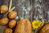 freshly baked pies, rolls, wheat bread with flax seeds, sunflower flower and rolling pin on brown wooden background 2