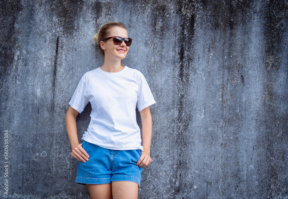 Female model wearing white blank t-shirt on the background of an gray scratched wall.