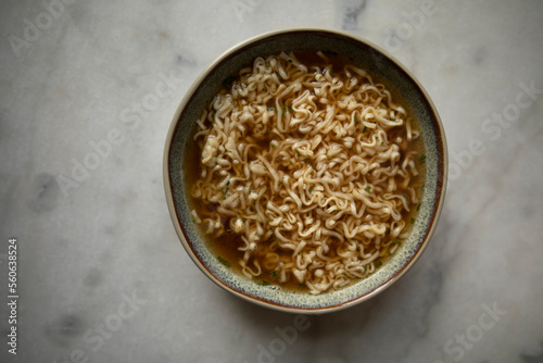 round plate with prepared instant noodles and black spoon close-up top view. ready ramen noodles. cooked ramen broth	