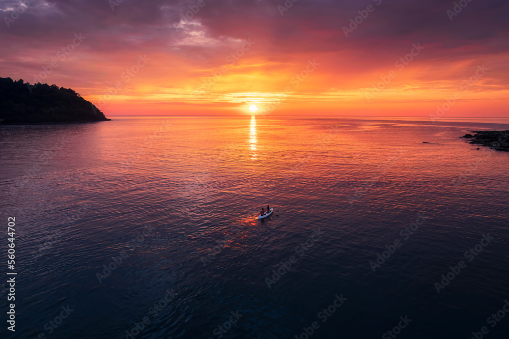 Beautiful sunset over tropical sea with tourists rowing canoe and enjoy the view in summer
