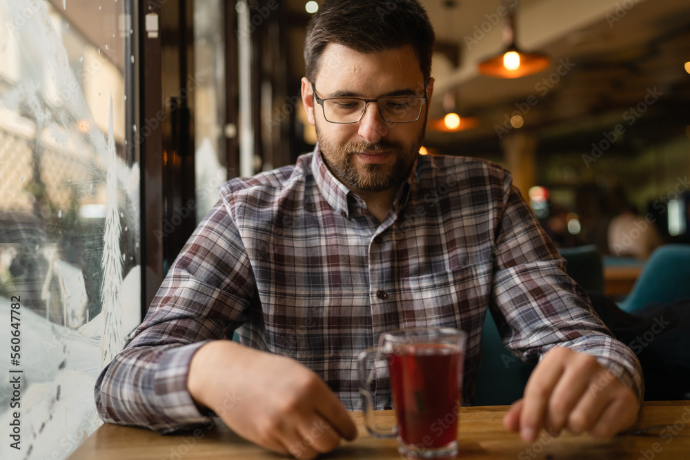 Bearded Man sitting alone at cafe or restaurant with glass cup of tea