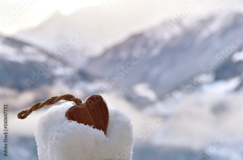 closeup on wooden  decorative heart put in the snow on mountain landscape bac...