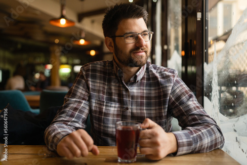 Bearded Man sitting alone at cafe or restaurant with glass cup of tea