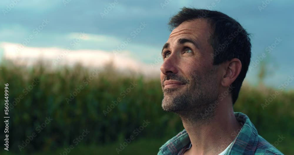 Happy Man Smiling and Looking Around in a Green Field of Corn. Handsome Middle-aged Male Farmer Enjoying the View, Thankful for the Good Weather, Hopeful for the Future of his Crops and Business Happy Man Smiling and Looking Around in a Green Field of Corn. Handsome Middle-aged Male Farmer Enjoying the View, Thankful for the Good Weather, Hopeful for the Future of his Crops and Business
