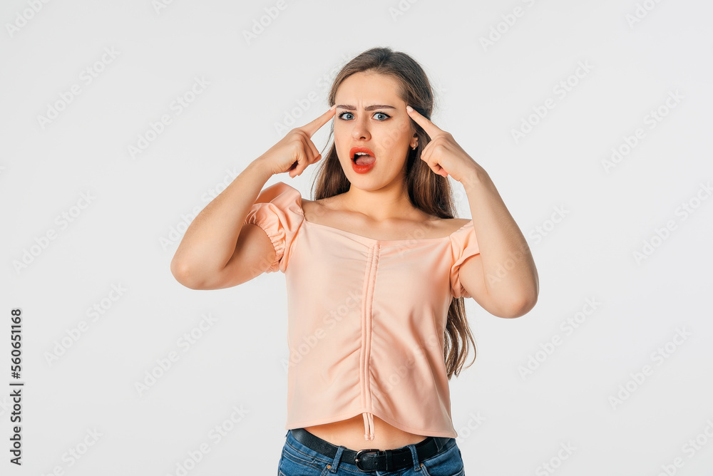 Young woman having a great idea. Portrait of surprised girl with long hair, pointing fingers at the temple, standing against white studio background Young woman having a great idea. Portrait of surprised girl with long hair, pointing fingers at the temple, standing against white studio background