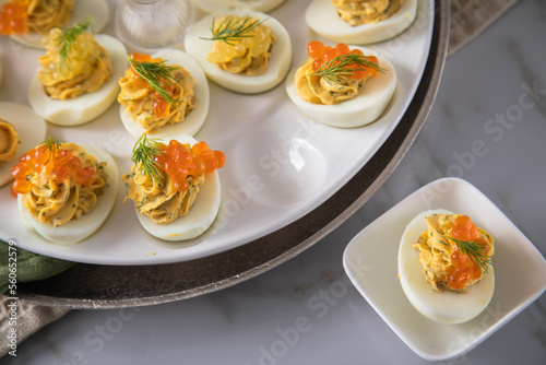 Gefüllte teuflische russische Eier mit Dill und orange Keta Lachs und gelb Saibling Kaviar auf Eierteller, Serviette grün, Silber Teller und Marmor Hintergrund hell photo