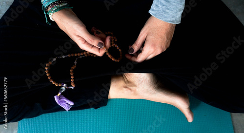 Woman's hands doing yoga while holding buddhist necklace