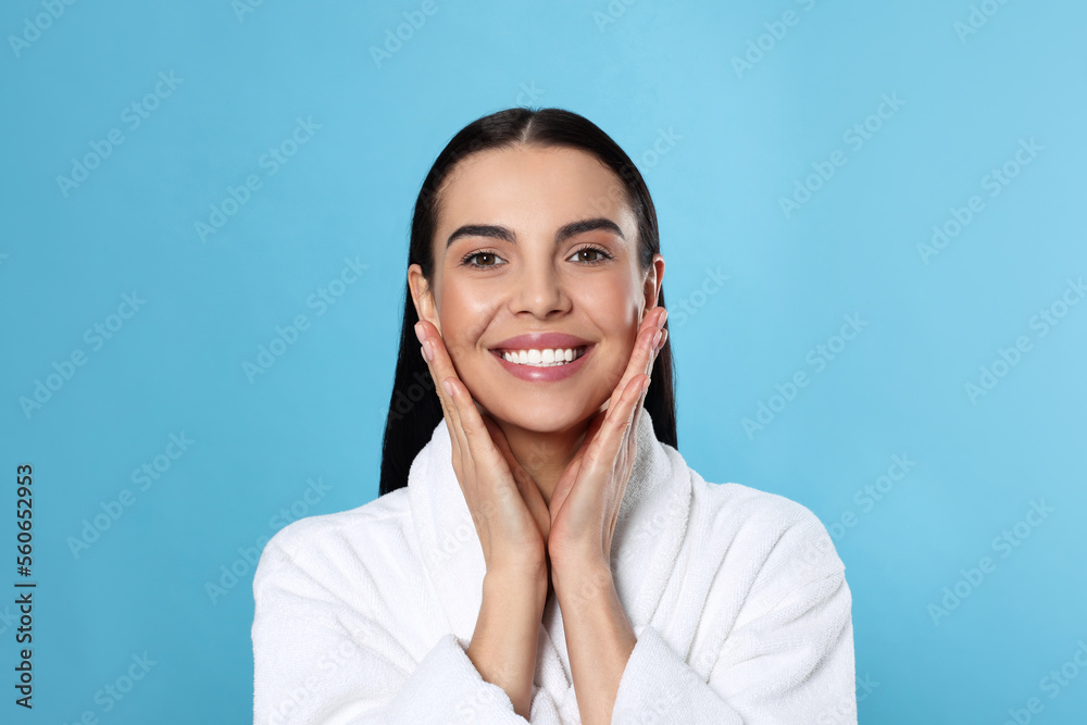 Portrait of attractive young woman in bathrobe on light blue background. Spa treatment Portrait of attractive young woman in bathrobe on light blue background. Spa treatment