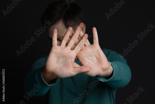 Man showing stop gesture against black background, focus on hands