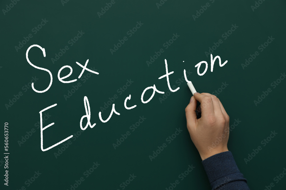 Man writing words Sex Education on green chalkboard, closeup Man writing words Sex Education on green chalkboard, closeup
