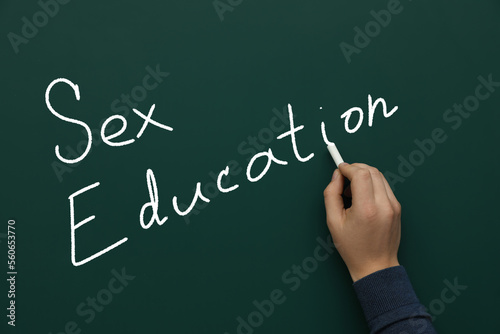 Man writing words Sex Education on green chalkboard, closeup
