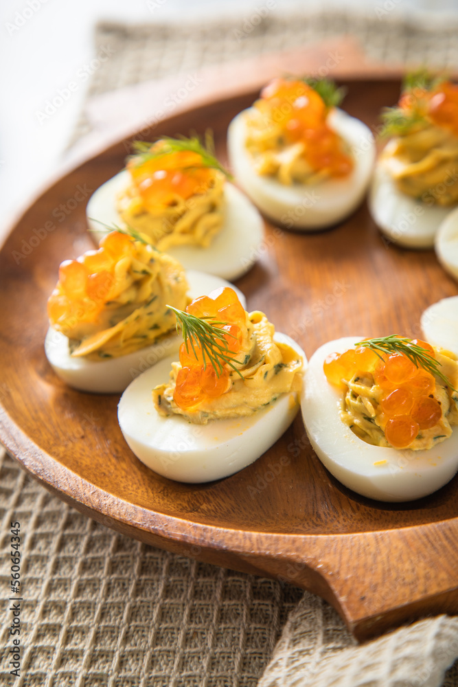 Gefüllte teuflische russische Eier mit Dill und orange Keta Lachs Kaviar auf Holz Eierteller und Serviette Gefüllte teuflische russische Eier mit Dill und orange Keta Lachs Kaviar auf Holz Eierteller und Serviette