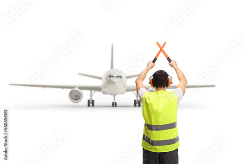 Rear view shot of a marshaller signalling with crossed wands in front of an aircraft photo