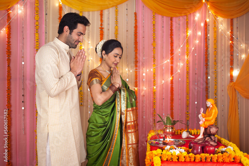 A smart Indian couple performing Sai pujan or puja on the occasion of Guru Purnima - Festival Celebration . A couple dressed in Indian traditional clothes is doing sai pooja - Indian culture and cu...