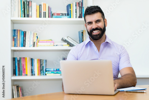 Laughing hispanic businessman with beard working at computer