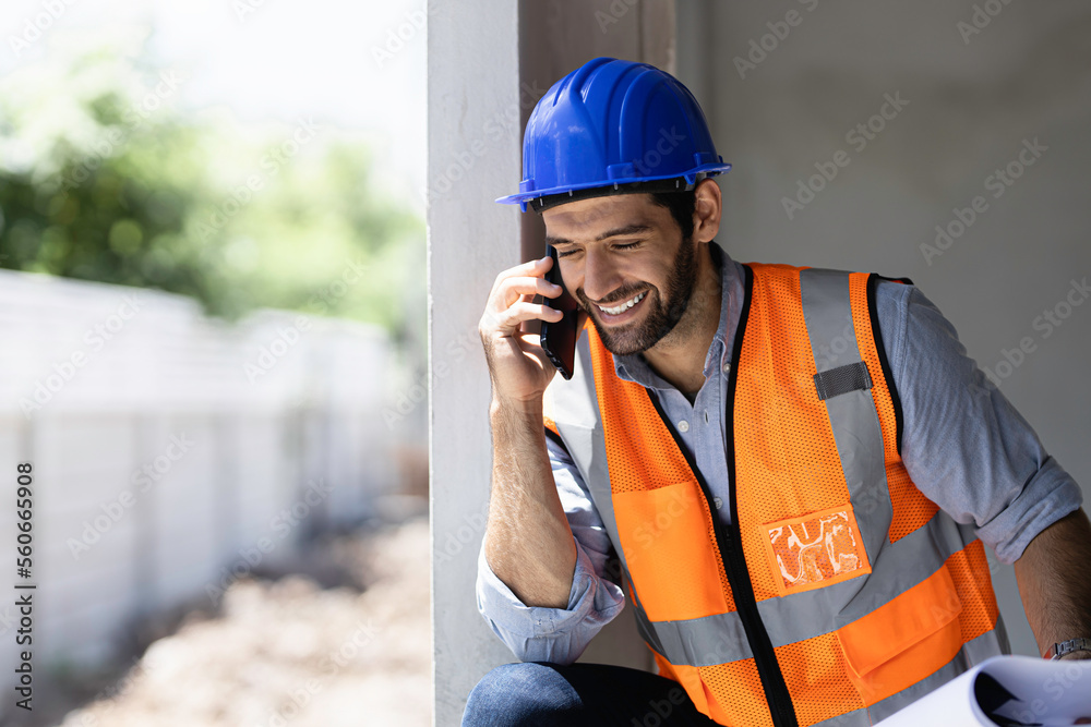 portrait of young engineer in vest with white helmet standing on construction site, smiling and holding smartphone for worker, internet, social media portrait of young engineer in vest with white helmet standing on construction site, smiling and holding smartphone for worker, internet, social media