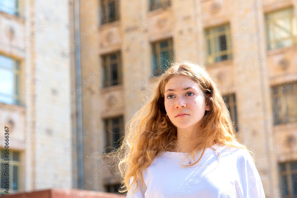 portrait of a beautiful teenager girl in front of school on a sunny day outside