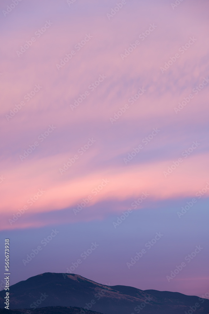 Stunning sunset with beautiful shades of orange, pink, purple and blue colors with the silhouette of a mountain range. Wallpaper, natural background with copy space.