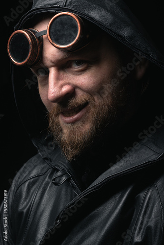 A man in a hood, wearing vintage steampunk goggles looking at the camera close-up