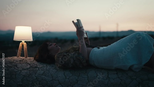 Girl reads a book on a rock with abat jour in the evening photo