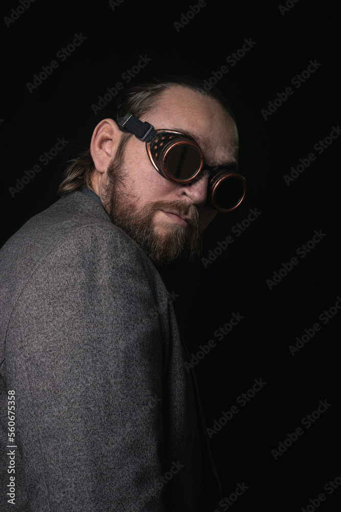Fototapeta premium charismatic man in a classic suit and steampunk goggles on a black background stylish Portrait