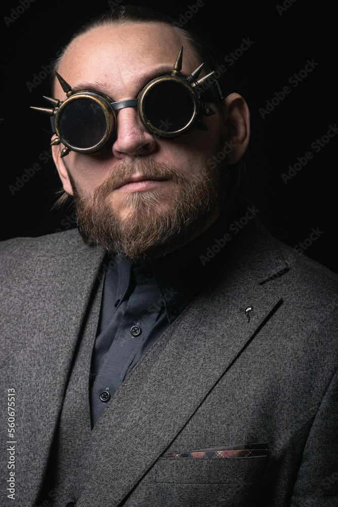 Obraz premium charismatic man in a classic suit and steampunk goggles on a black background stylish Portrait