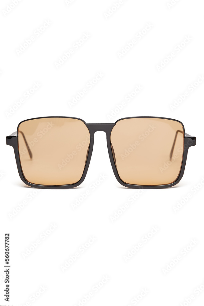 Close-up shot of women's square sunglasses with a thin black frame and brown lenses. The oversized sunglasses are isolated on a white background. Front view. Close-up shot of women's square sunglasses with a thin black frame and brown lenses. The oversized sunglasses are isolated on a white background. Front view.