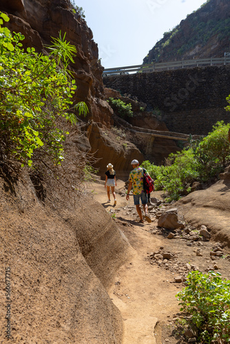 travelers walk along the tourist trail leading to Las Vacas canyon in Gran Canaria, Spain