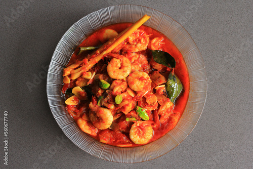 Chili prawns or Sambal Udang with petai or pete or mlanding (Parkia speciosa) cooked with mashed red chili and tomato in clear plate, with black background, top view.  Indonesia cuisine food.