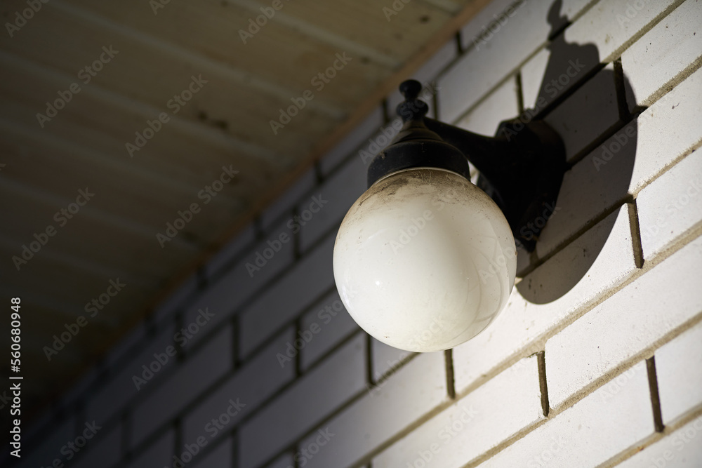 A round wall lamp on the wall of a brick house