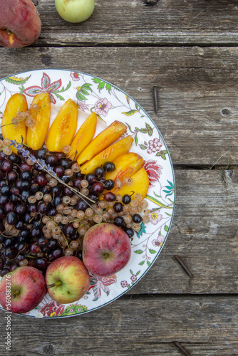 apples, peaches and black currants on a plate.