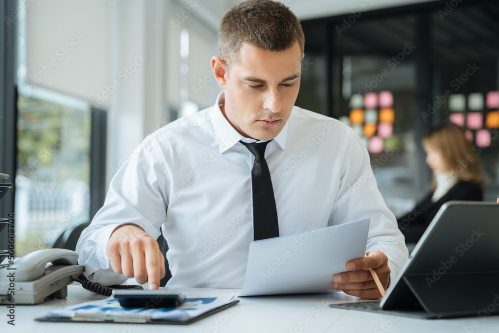 Business man using digital tablet analyzes business data, busy working on laptop computer with smart phone and business report on office desk, business strategy analysis concept. Business man using digital tablet analyzes business data, busy working on laptop computer with smart phone and business report on office desk, business strategy analysis concept.