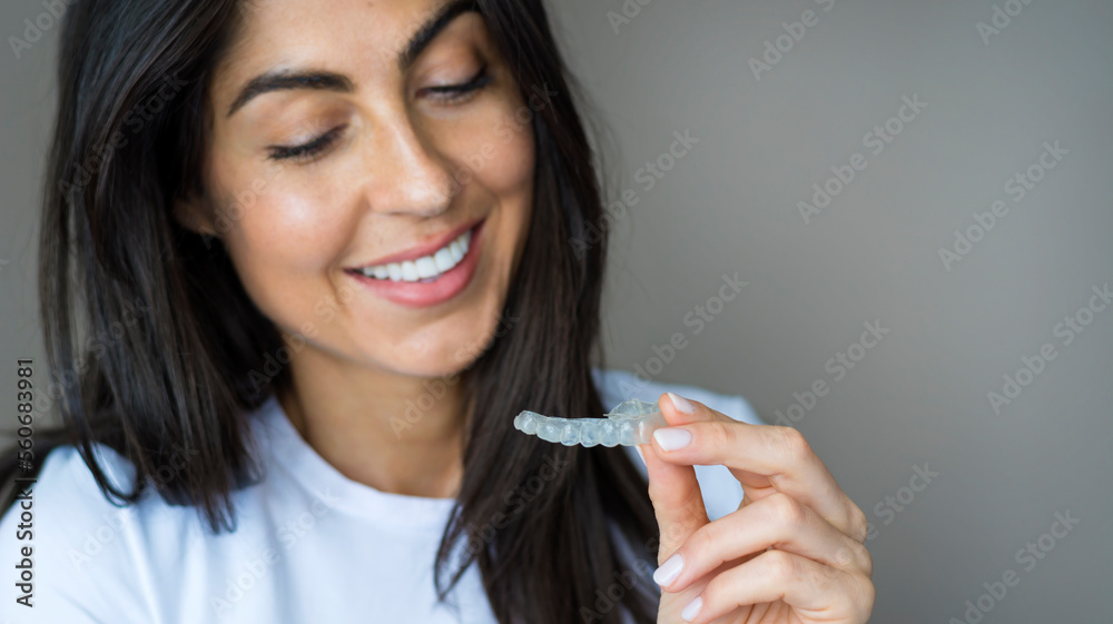 Teeth whitening. Woman with white smile holding removable braces . Invisible teeth tray . Orthodontic silicone trainer. Invisible braces aligner. Teeth whitening. Woman with white smile holding removable braces . Invisible teeth tray . Orthodontic silicone trainer. Invisible braces aligner.