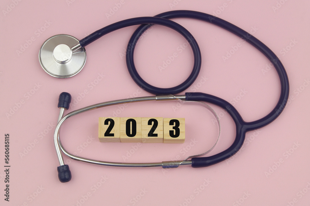 Stethoscope and numbers 2023 on wooden cubes on pink background. Medicine and health care changes in year 2023 concept. Stethoscope and numbers 2023 on wooden cubes on pink background. Medicine and health care changes in year 2023 concept.