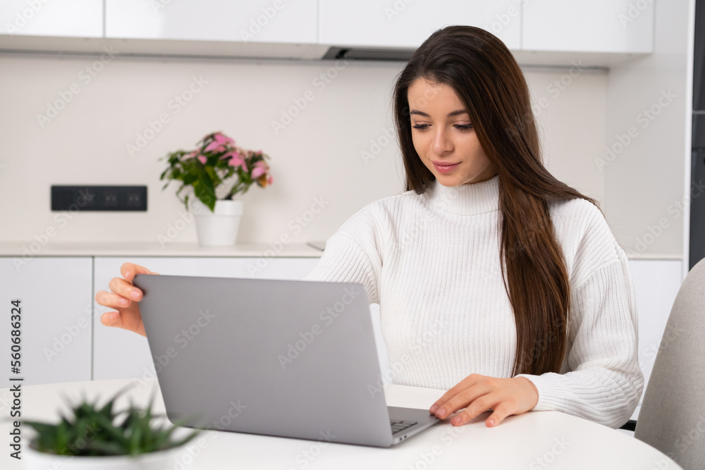 Young beautiful woman sits at her workplace and opens the laptop for working online. Freelance working at home. Young beautiful woman sits at her workplace and opens the laptop for working online. Freelance working at home.