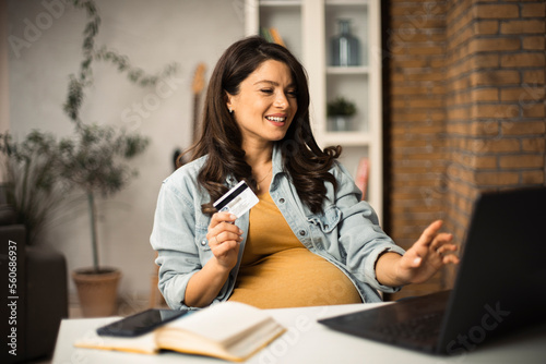 Pregnant woman shopping online at home. Happy woman with laptop and credit card..