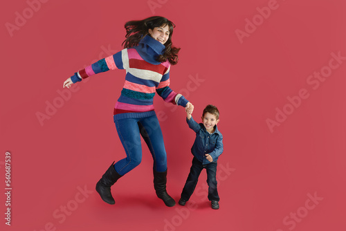 A mother with her son have fun jumping on a magenta background in studio.