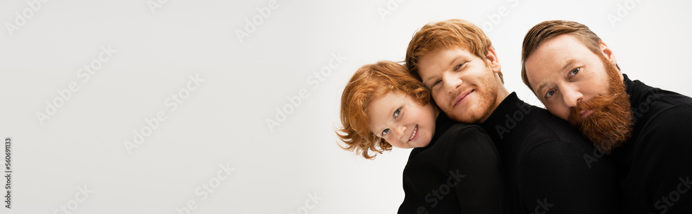 happy boy with bearded grandpa and father in black turtlenecks leaning on each other isolated on grey, banner. happy boy with bearded grandpa and father in black turtlenecks leaning on each other isolated on grey, banner.