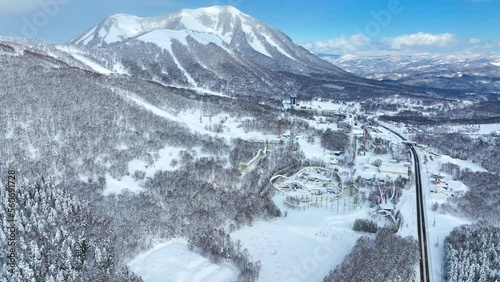 flying above breathtaking winter road in snowy mountains at a ski resort, ski slopes in Hokkaido, Japan, scenic winter forest at a ski resort photo
