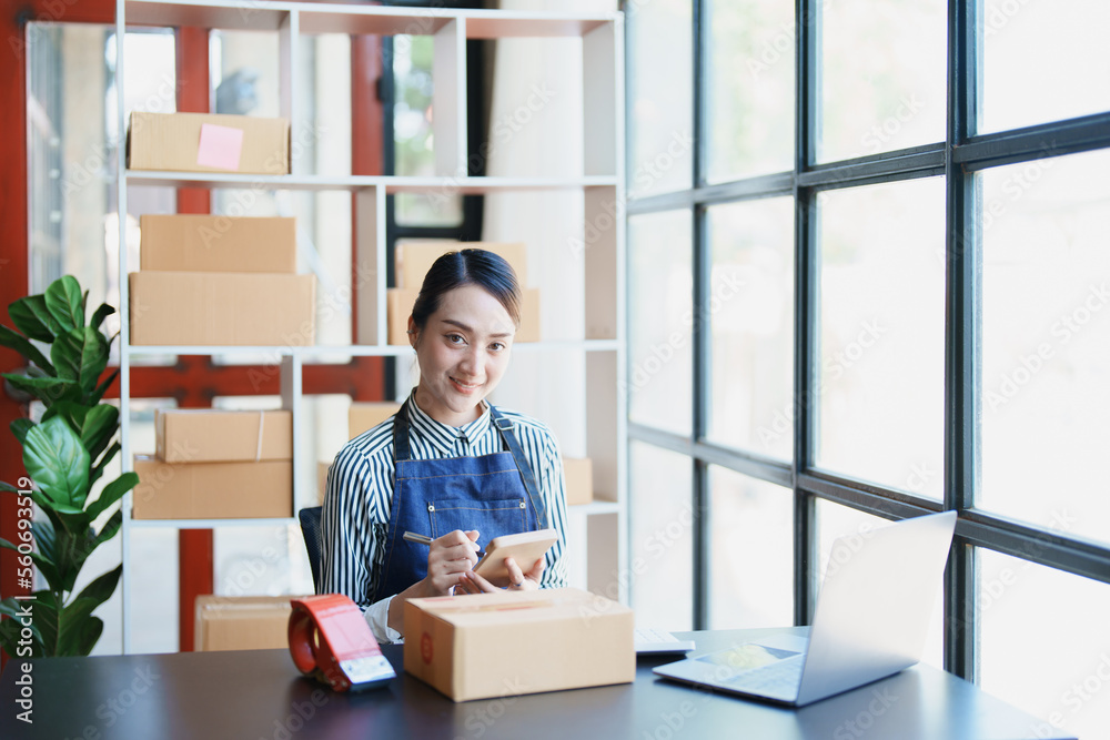 Starting small business entrepreneur of independent young Asian woman online seller is using computer and taking orders to pack products for delivery to customers. SME delivery concept Starting small business entrepreneur of independent young Asian woman online seller is using computer and taking orders to pack products for delivery to customers. SME delivery concept
