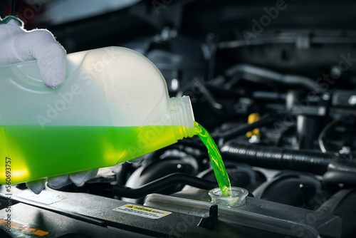 pouring antifreeze coolant liquid into car engine radiator photo