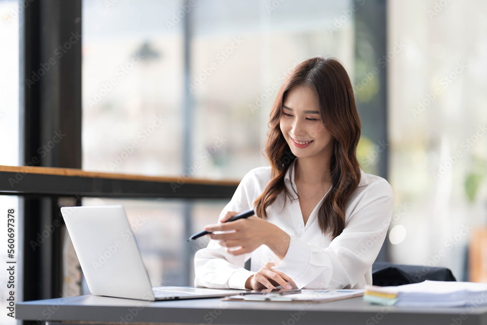 Young beautiful asian businesswoman working on tablet with happiness while sitting at the table in modern office room. Young beautiful asian businesswoman working on tablet with happiness while sitting at the table in modern office room.