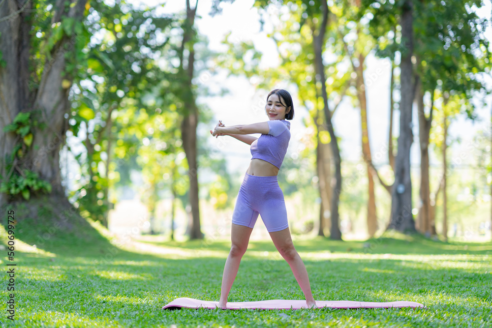 Attractive and strong Asian woman with a beautiful body. yoga in graceful posture in the green park Modern concept of relaxation and health care.